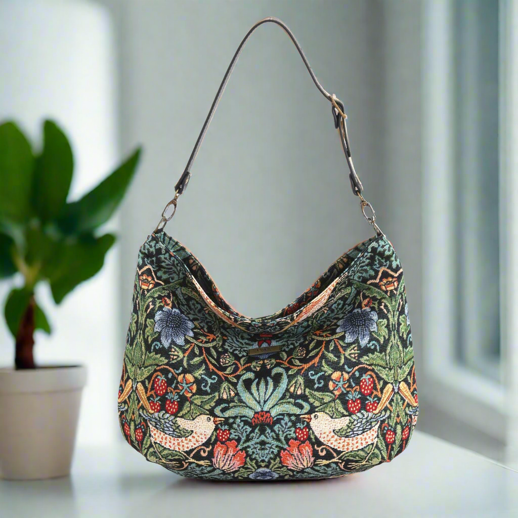 Luxurious hobo bag featuring William Morris's iconic Strawberry Thief pattern in rich indigo blue with delicate birds and strawberry motifs, crafted with premium fabric and leather trim, front view showcasing the elegant curved silhouette by Umpie Handbags