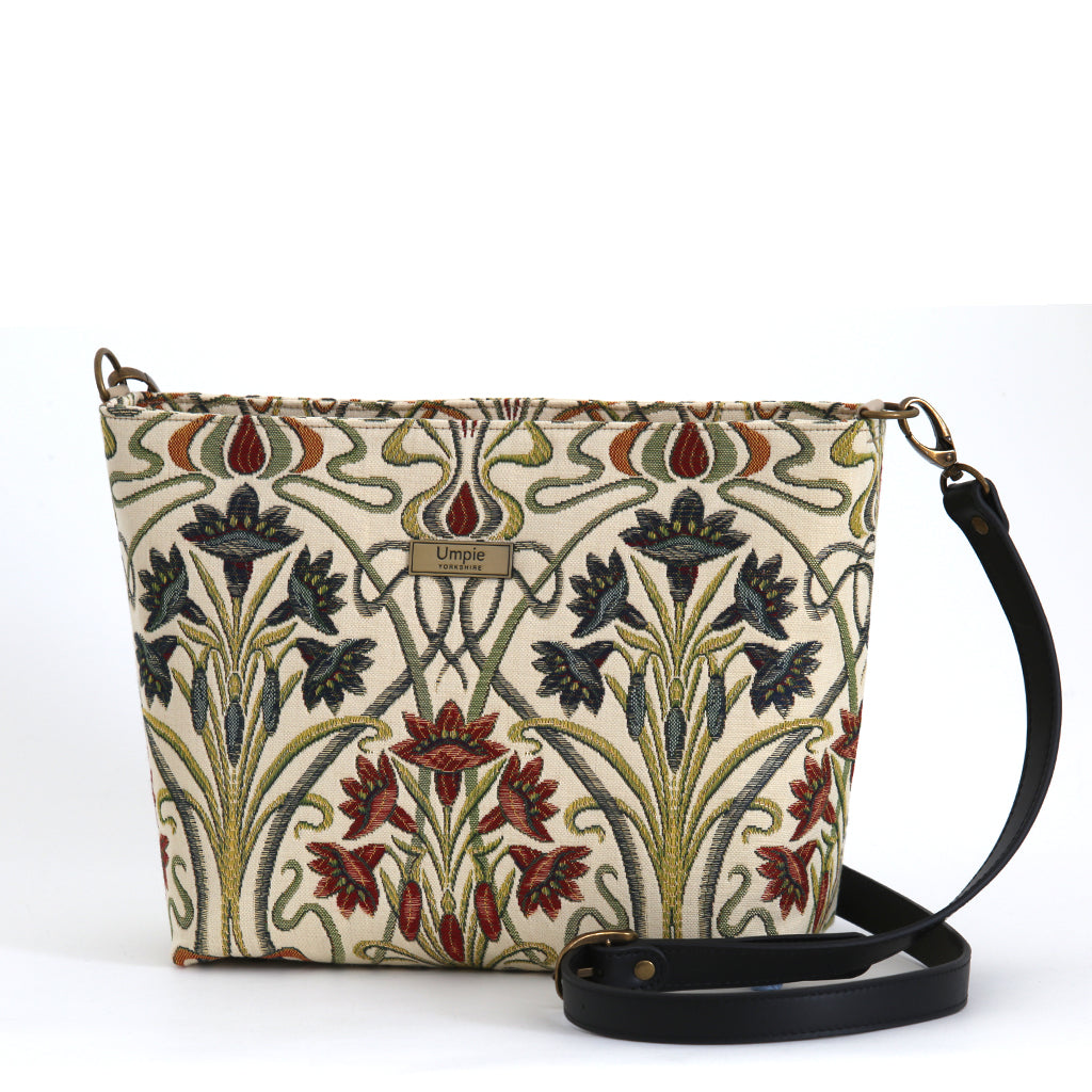 Art Nouveau Crossbody Bag front view — cream woven tapestry with deep navy, burgundy and sage iris florals, black leather strap and antique brass hardware, by Umpie Handbags