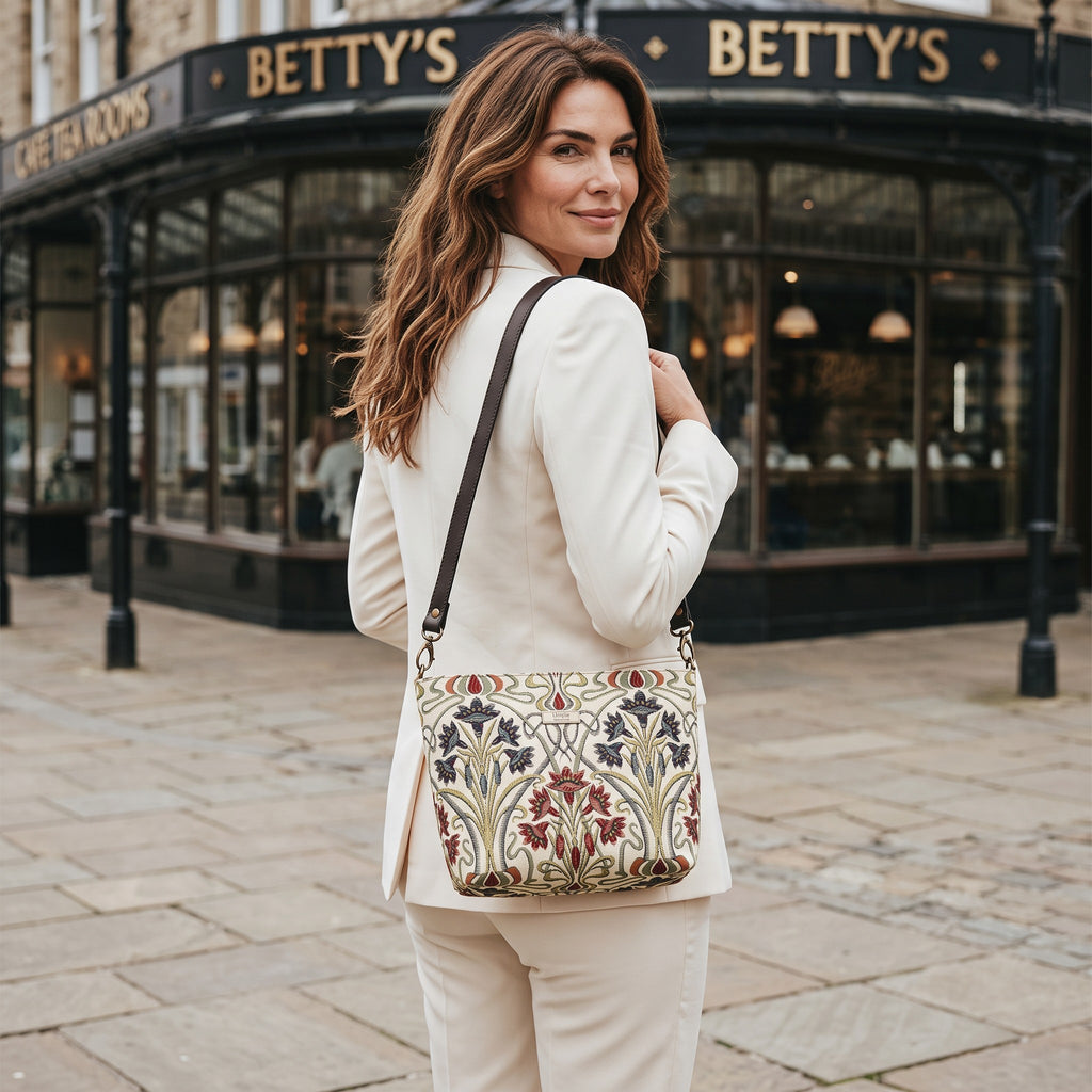 Art Nouveau Crossbody Bag worn over the shoulder outside Betty's Tea Rooms, Harrogate — richly embroidered tapestry fabric with navy and burgundy florals, by Umpie Handbags
