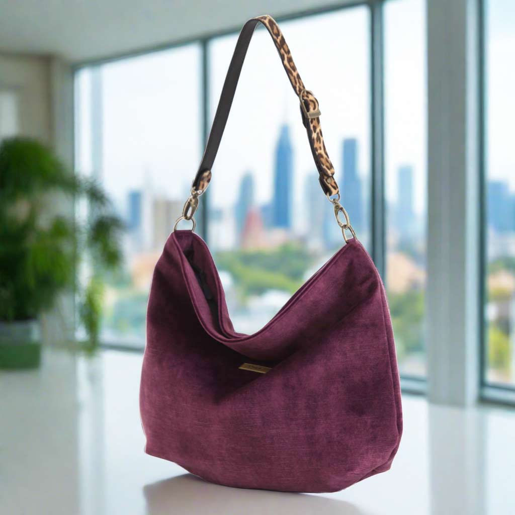 Luxurious aubergine velvet hobo bag in rich deep purple with sumptuous soft texture, featuring bold leopard-print leather strap with brass hardware, elegant slouchy silhouette - front view by Umpie Handbags