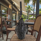 Black lizard print hobo bag standing upright on a wicker chair, showing black leather strap and gold clasp hardware, by Umpie Handbags