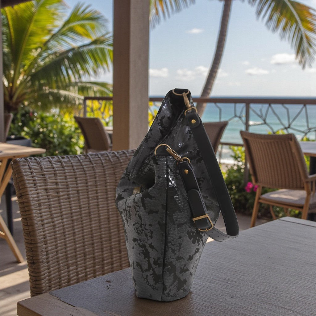 Black lizard print hobo bag resting in a wicker chair showing relaxed slouchy silhouette and textured fabric detail, by Umpie Handbags