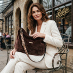 Model seated outside Bettys Café, York, holding the brown velvet hobo bag with matching brown leopard print strap and antique gold hardware by Umpie Handbags