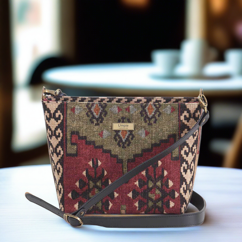 The Artisan Kilim Crossbody Bag sitting on a cafe table, by Umpie Handbags