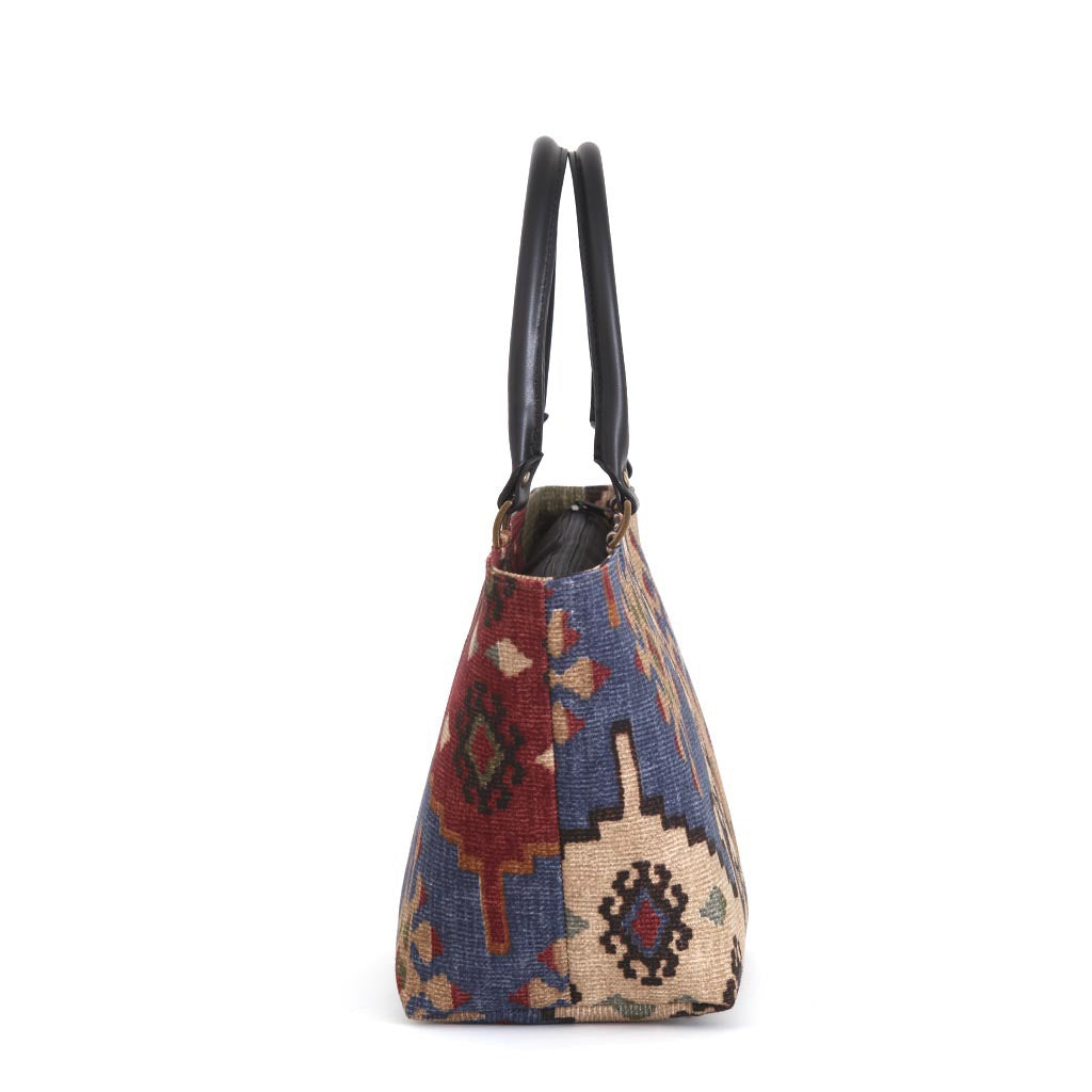 Side profile of canvas handbag showing structured depth and shape, authentic Kilim pattern in burgundy and navy geometric design, premium black leather handles, and individually handcrafted quality by Umpie Handbags