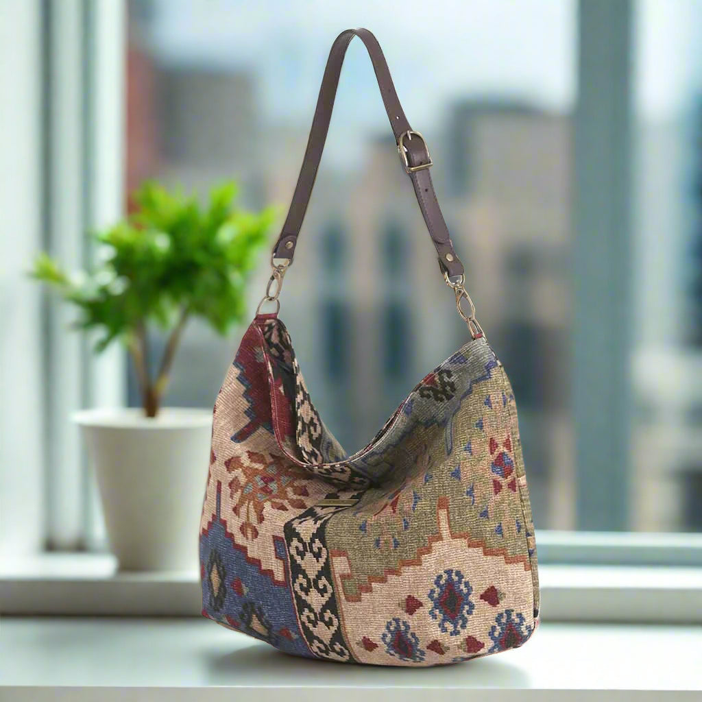 The Canvas Hobo Bag, Kilim Design with a brown leather strap.