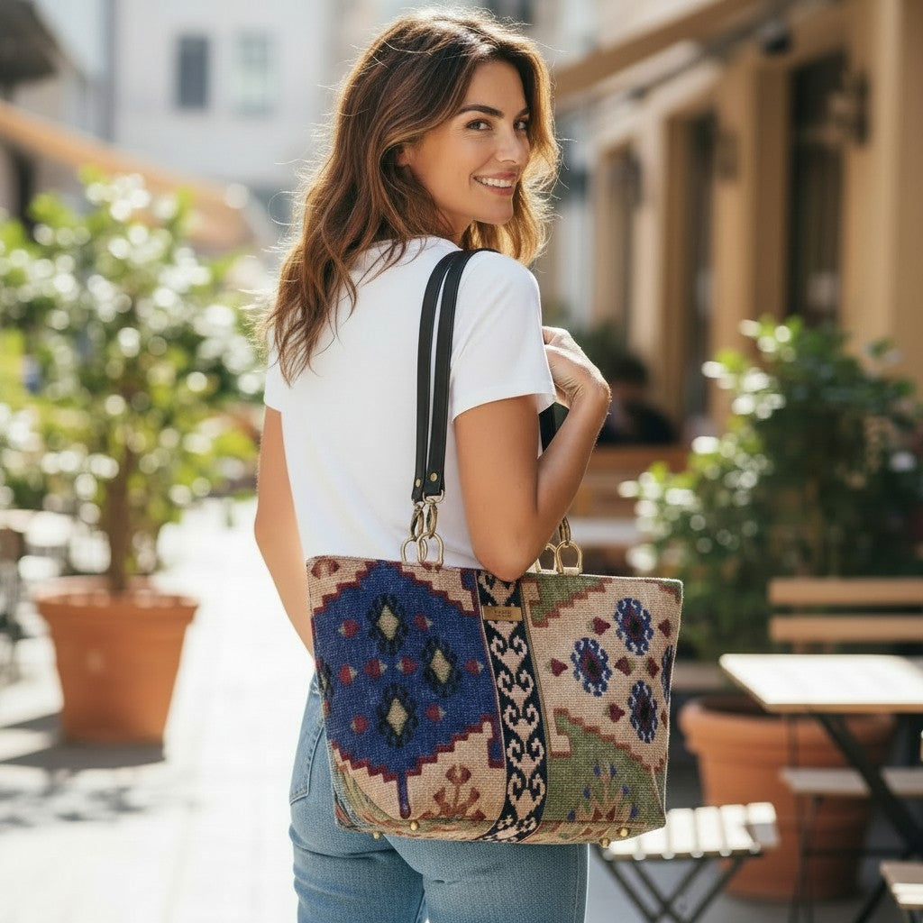 Model carrying canvas shoulder bag featuring authentic Kilim geometric pattern in rich navy, green and taupe tones with premium black leather straps, showcasing comfortable shoulder wear and hands-free styling with heritage textile design by Umpie Handbags