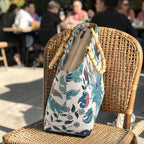Top-down view of a floral linen handbag with bamboo handles on a chair, revealing the secure zip closure and the structured linen body that holds its shape beautifully, by Umpie Handbags