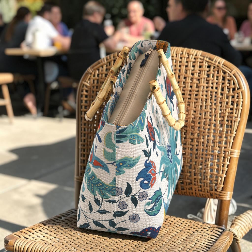 Top-down view of a floral linen handbag with bamboo handles on a chair, revealing the secure zip closure and the structured linen body that holds its shape beautifully, by Umpie Handbags