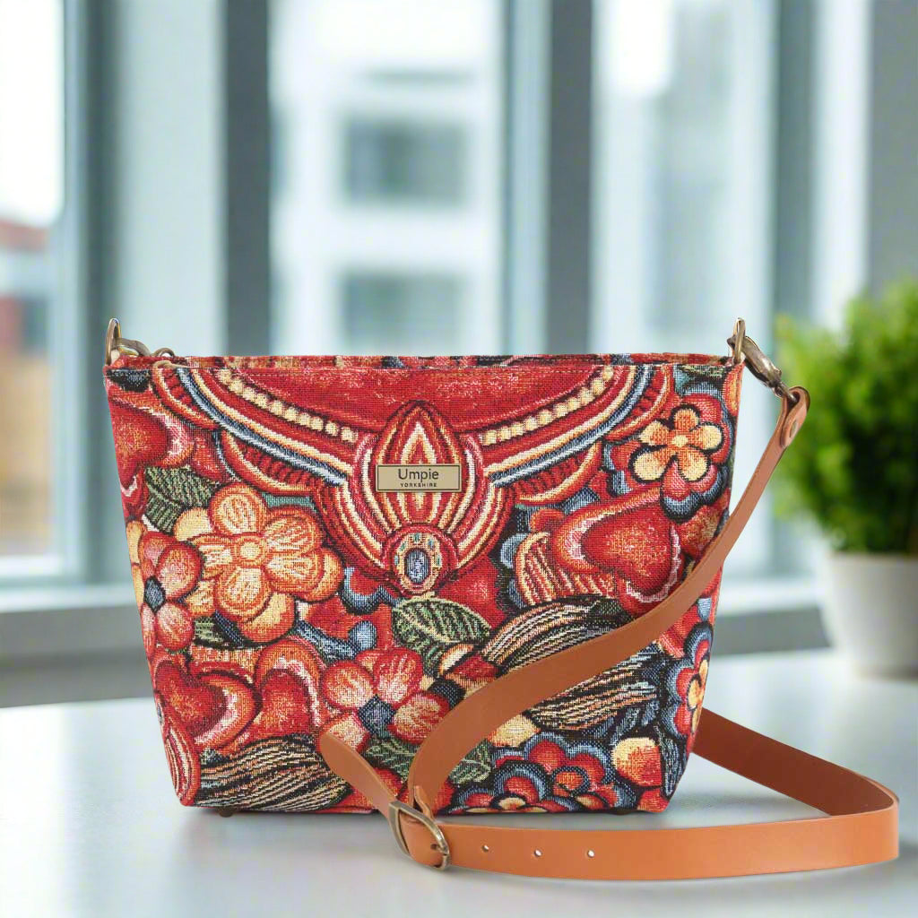 The Red Floral Crossbody Bag with a tan leather strap.
