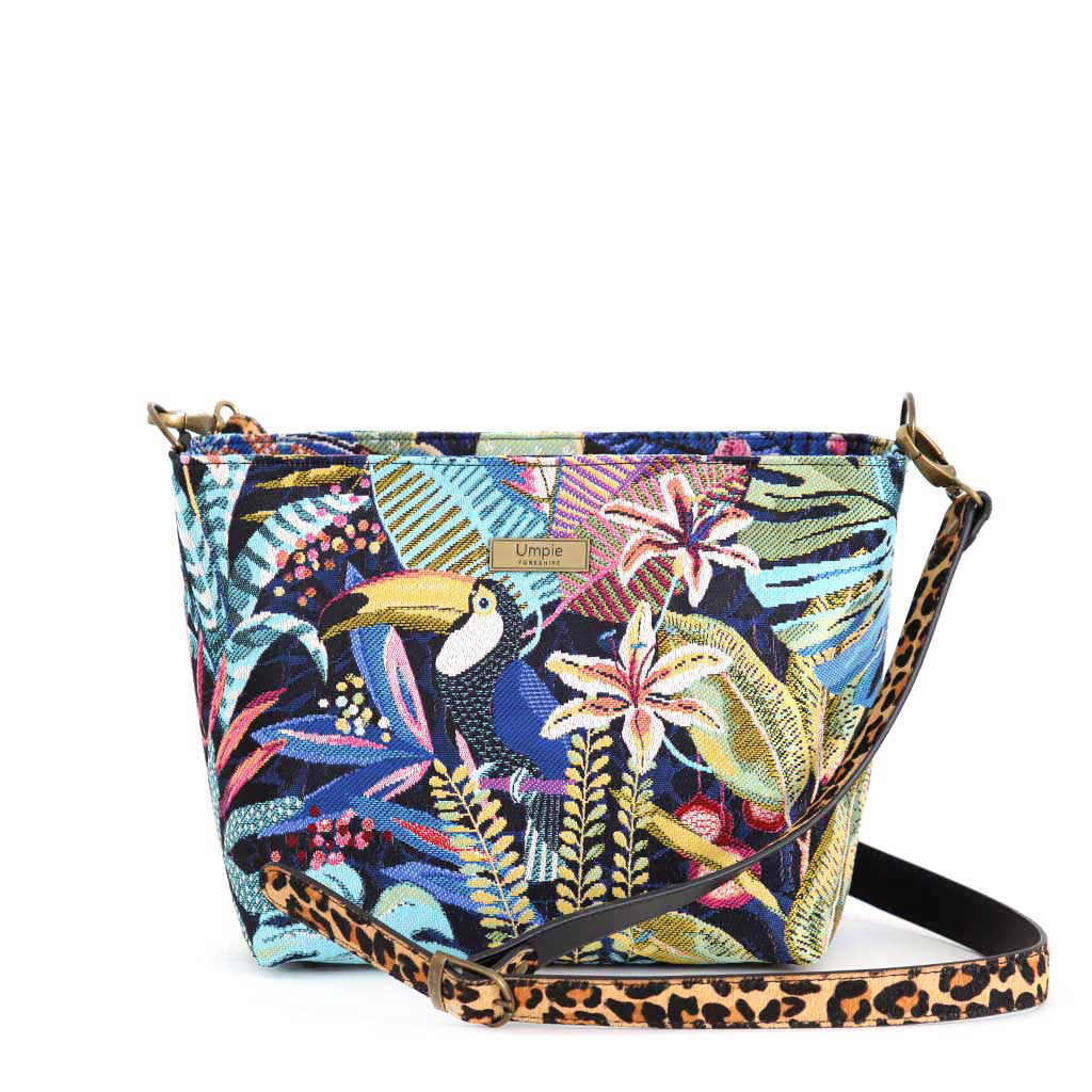 Full view of handcrafted floral crossbody bag featuring vibrant botanical print in greens and corals, adjustable leopard print leather strap, top-zip security, and sustainable British-made quality by Umpie Handbags