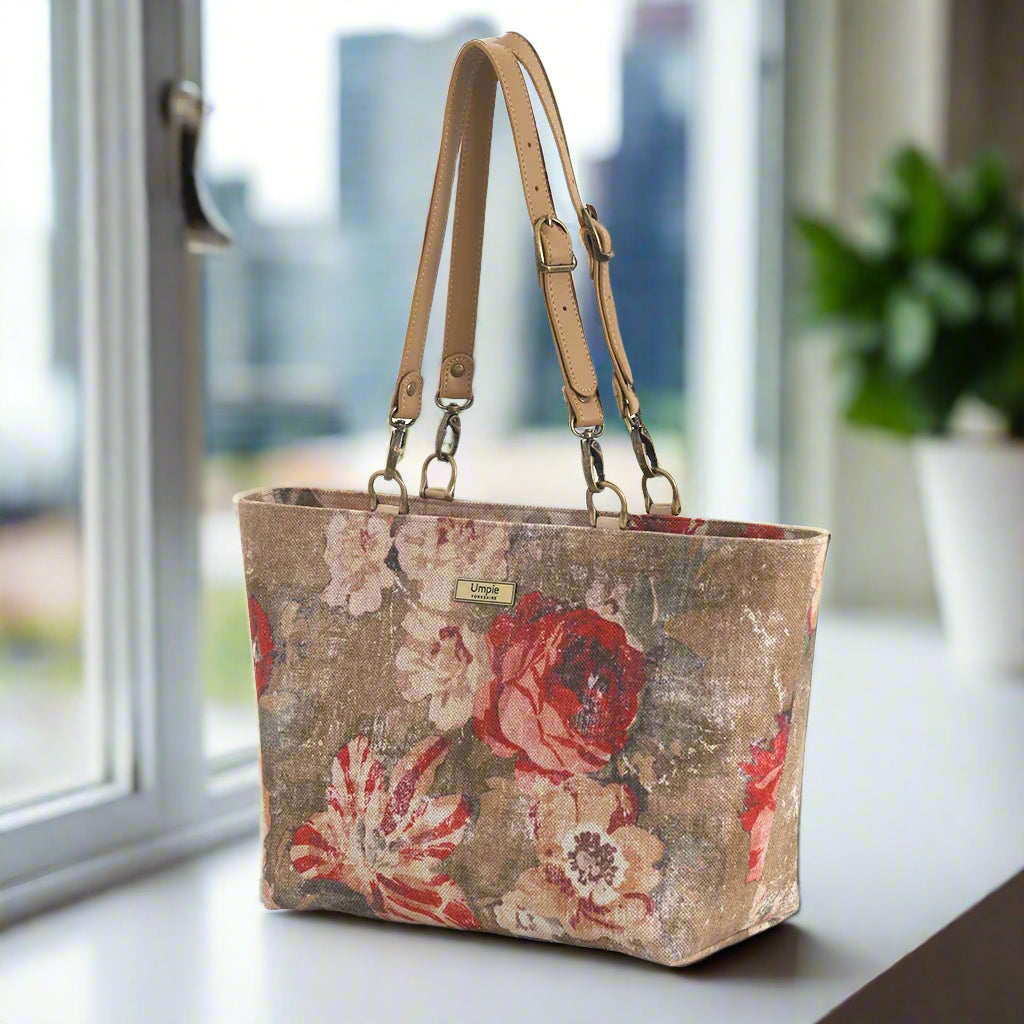 A woman&#39;s shoulder bag in a beige and red antique-style floral fabric with matching leather straps