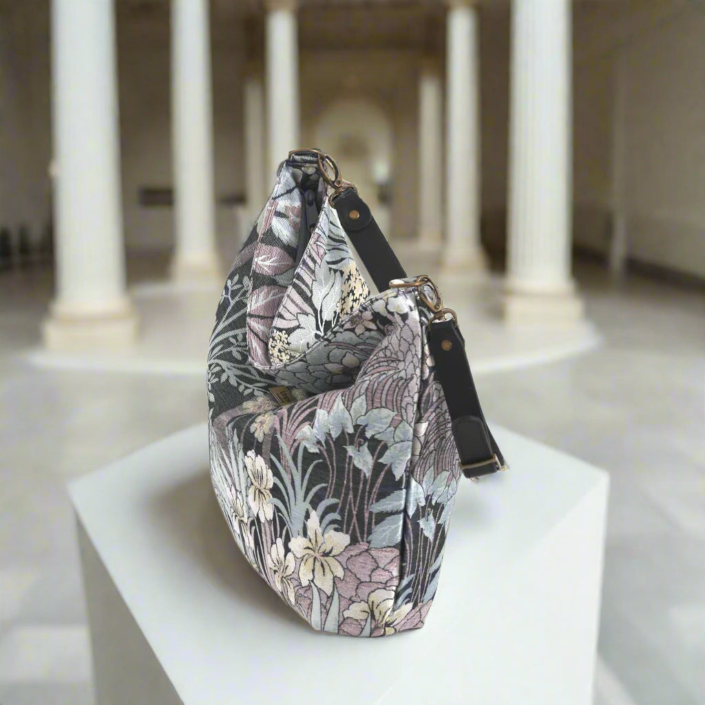 The Grey Floral Hobo Bag with a black leather strap, zip-top view