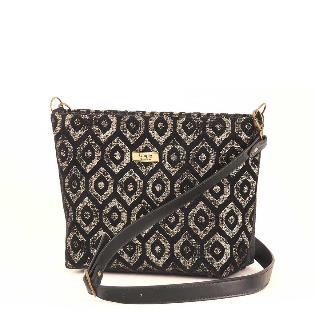 Gold metallic crossbody bag displayed at three-quarter angle, highlighting the premium black leather adjustable strap, fully lined interior with zip-top closure, and elegant proportions of handcrafted design by Umpie Handbags