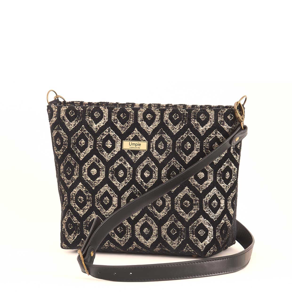 Gold metallic crossbody bag displayed at three-quarter angle, highlighting the premium black leather adjustable strap, fully lined interior with zip-top closure, and elegant proportions of handcrafted design by Umpie Handbags
