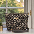  Luxurious gold metallic fabric crossbody bag with sleek black leather strap, featuring firm structured construction and protective metal feet on base, front view showcasing shimmering surface and zip-top closure by Umpie Handbags