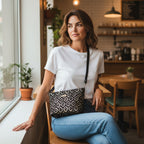 Woman sitting in a cafe wearing the Gold Metallic Crossbody Bag worn across body showing shimmering gold fabric and black leather strap by Umpie Handbags