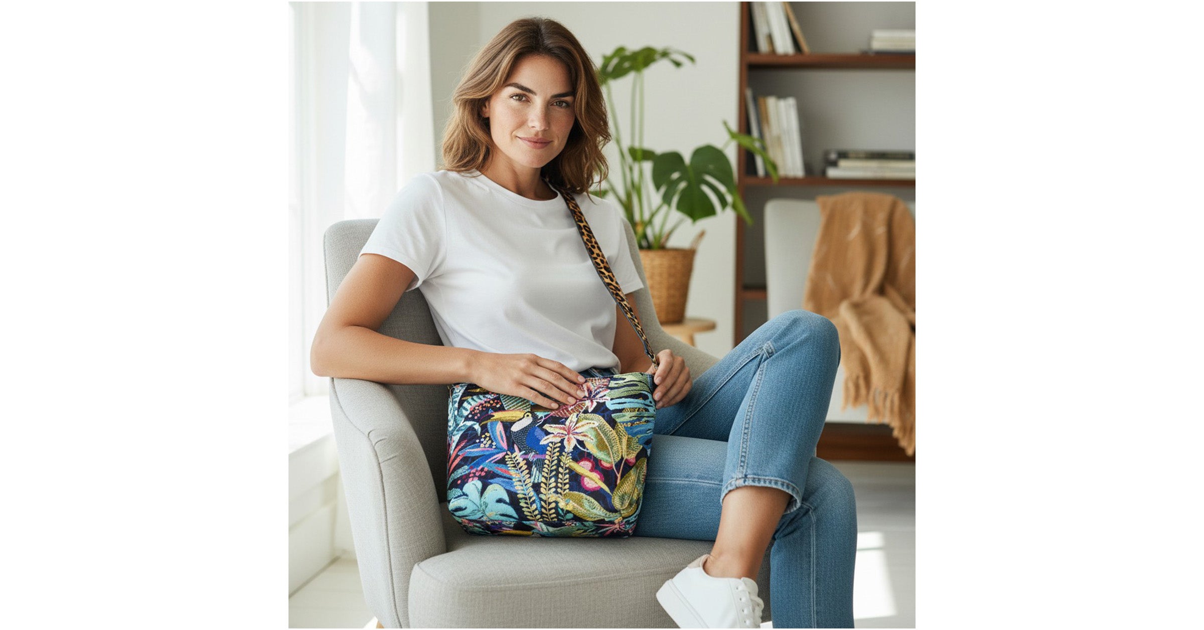 Model sitting with the vibrant floral crossbody bag featuring tropical botanical print in lush greens and coral tones with adjustable leopard print leather strap, showcasing hands-free everyday styling and sustainable eco-friendly fabric by Umpie Handbags