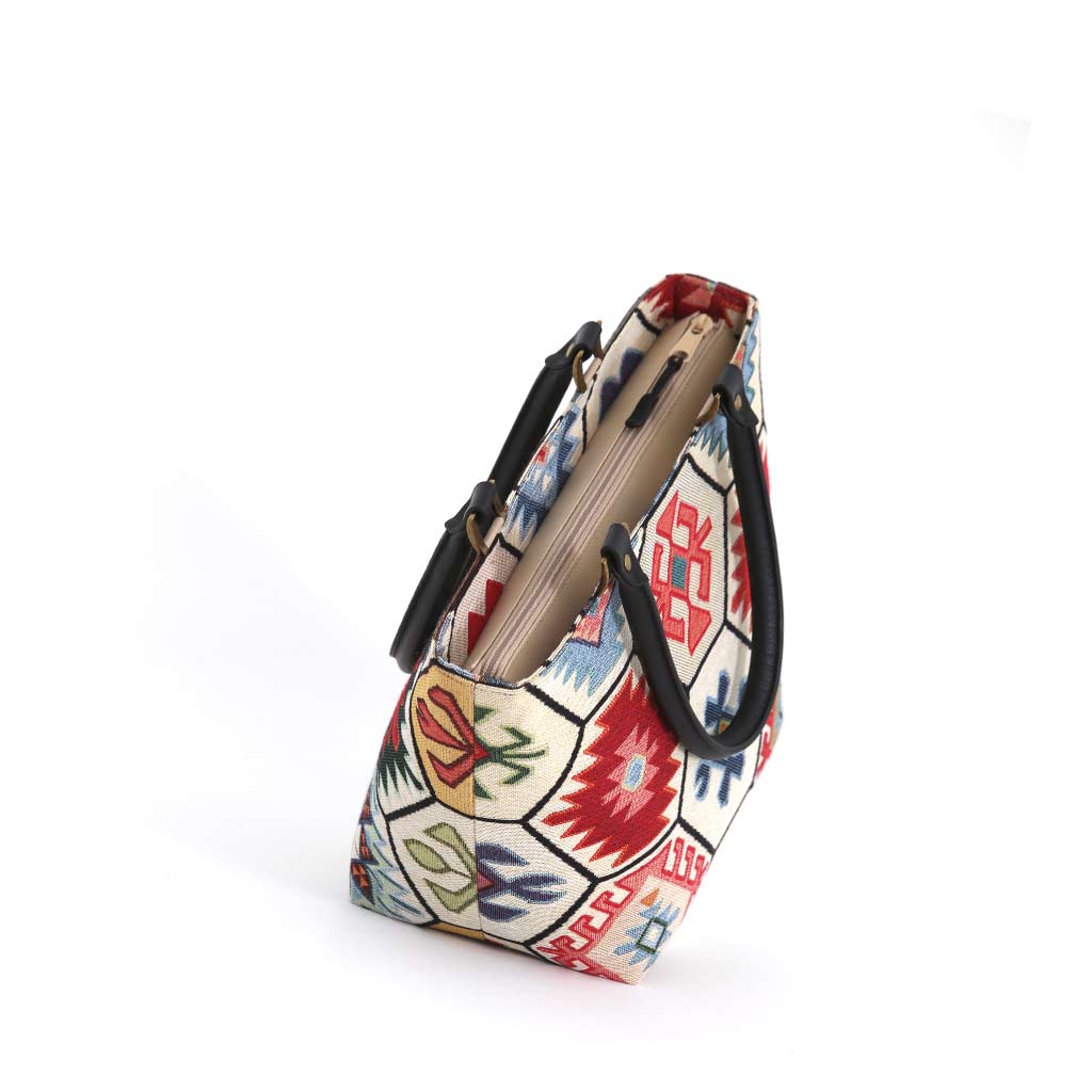 Zip-top view of the Hexagon Handbag revealing the structured trapezoid shape with the kilim-inspired tapestry body and black leather handles with antique brass fittings visible, handmade in Yorkshire by Umpie Handbags


