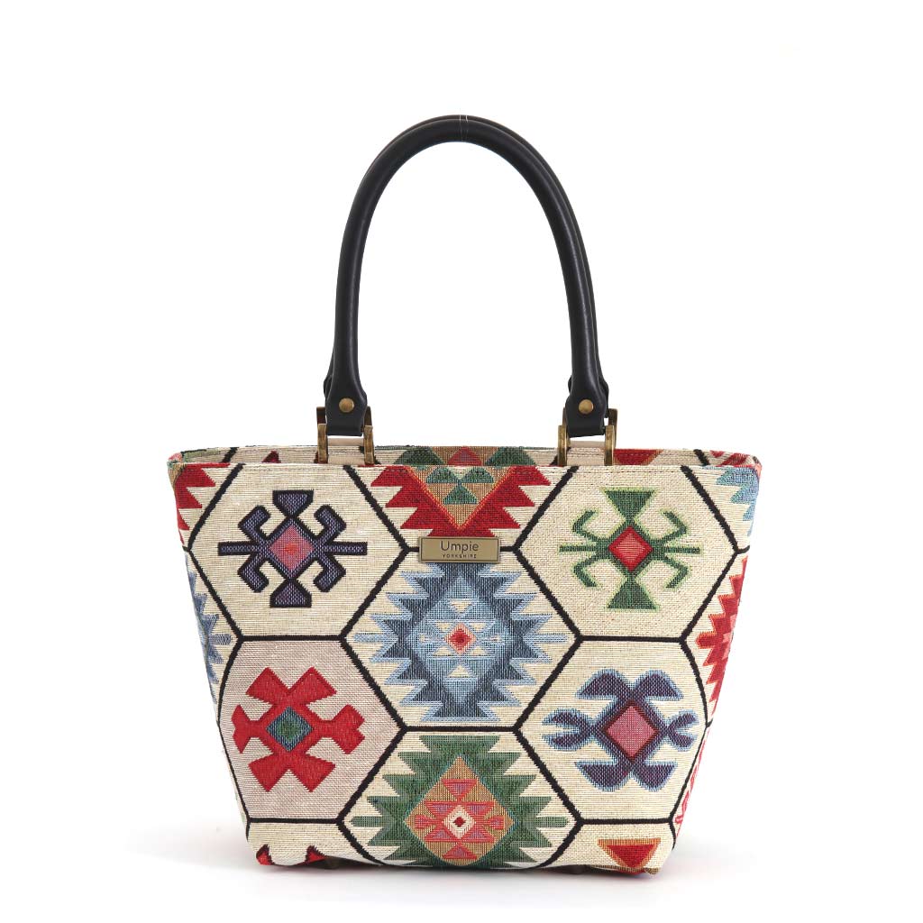 Hexagon Handbag in multicoloured kilim-inspired tapestry fabric with geometric hexagon panels, black leather top handles and antique brass hardware, handmade in Yorkshire by Umpie Handbags