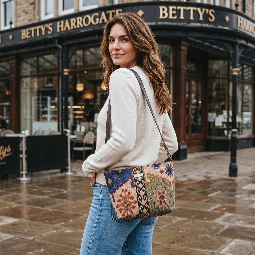 Model outside Betty's Harrogate with the Kilim canvas crossbody bag, rich geometric Kilim pattern in navy and green, handmade in Great Britain by Umpie Handbags