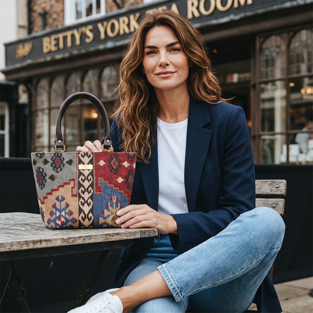 A woman sitting outside Bettys in Yorks holding the Artisan Kilim Canvas Handbag by Umpie Yorkshire