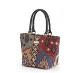 Three-quarter angle of Kilim canvas handbag revealing spacious interior capacity, durable canvas construction with traditional geometric weaving pattern, and premium black leather handle attachment by Umpie Handbags