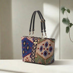 Front view of Kilim canvas shoulder bag displaying traditional geometric weaving pattern in rich navy, green and taupe, durable canvas construction, premium black leather straps with quality hardware, and British craftsmanship by Umpie Handbags