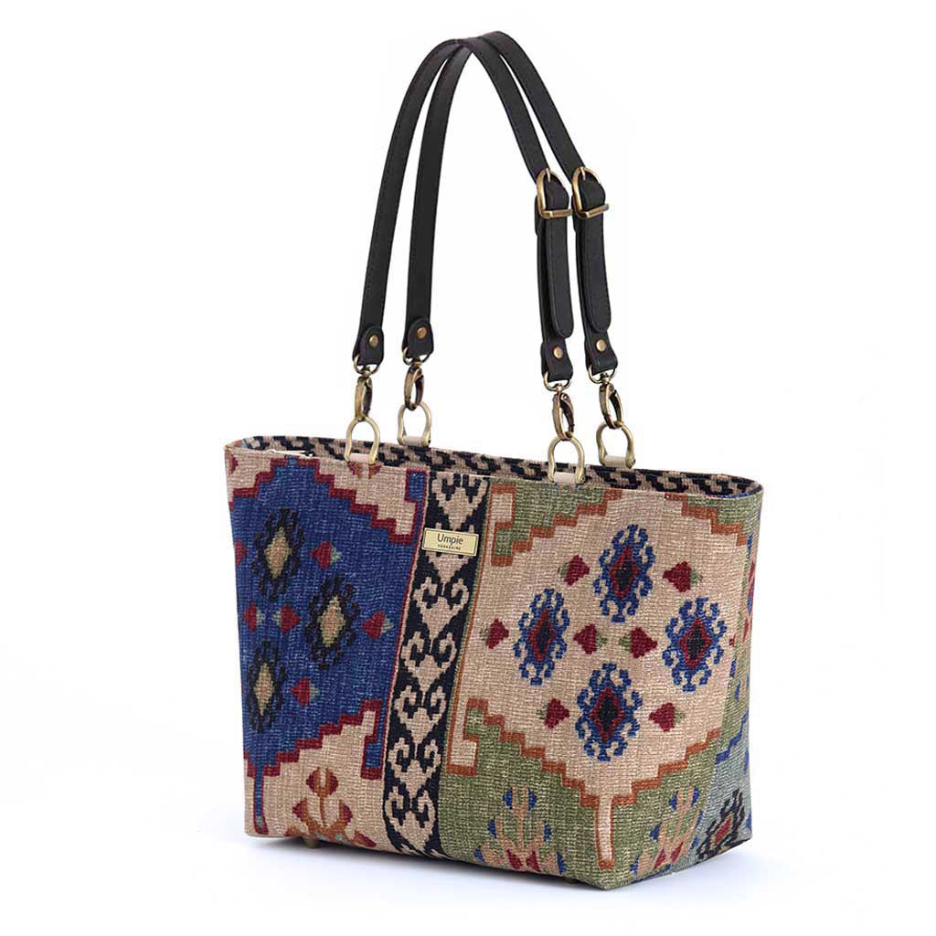 Front view of Kilim canvas shoulder bag displaying traditional geometric weaving pattern in rich navy, green and taupe, durable canvas construction, premium black leather straps with quality hardware, and British craftsmanship by Umpie Handbags
