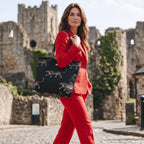 Model carrying luxurious black embroidered tapestry leopard tote bag featuring bold animal print pattern and premium black leather straps, showcasing spacious silhouette and comfortable shoulder carry for everyday style by Umpie Handbags