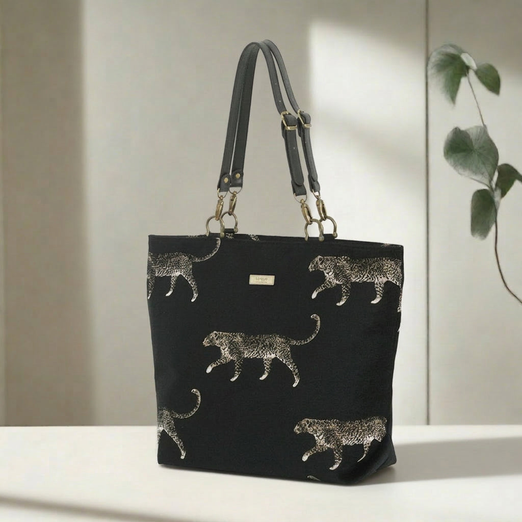 Full front view of leopard tote bag showcasing striking embroidered animal print on black tapestry, comfortable black leather shoulder straps, spacious interior, and individually handcrafted British quality by Umpie Handbags