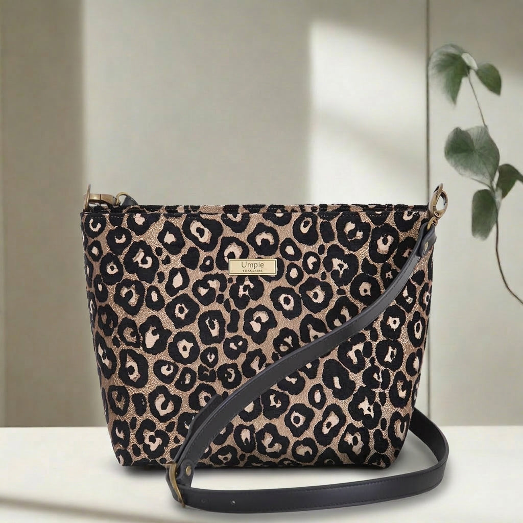 Compact leopard print crossbody bag displayed at an angle, showcasing the eye-catching metallic sheen and structured silhouette with premium black leather strap by Umpie Handbags