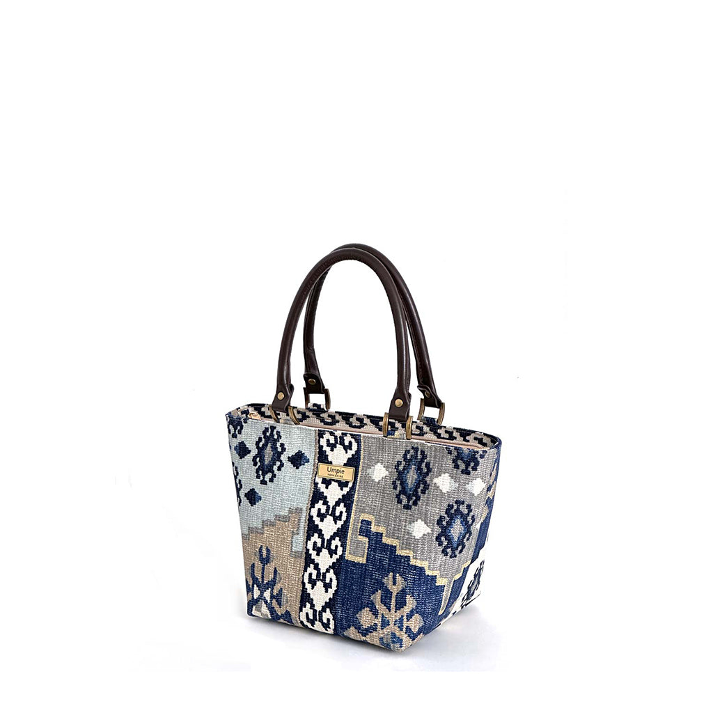Navy canvas handbag with traditional Kilim geometric pattern in navy, grey, light blue and taupe, brown leather handles, front view by Umpie Handbags