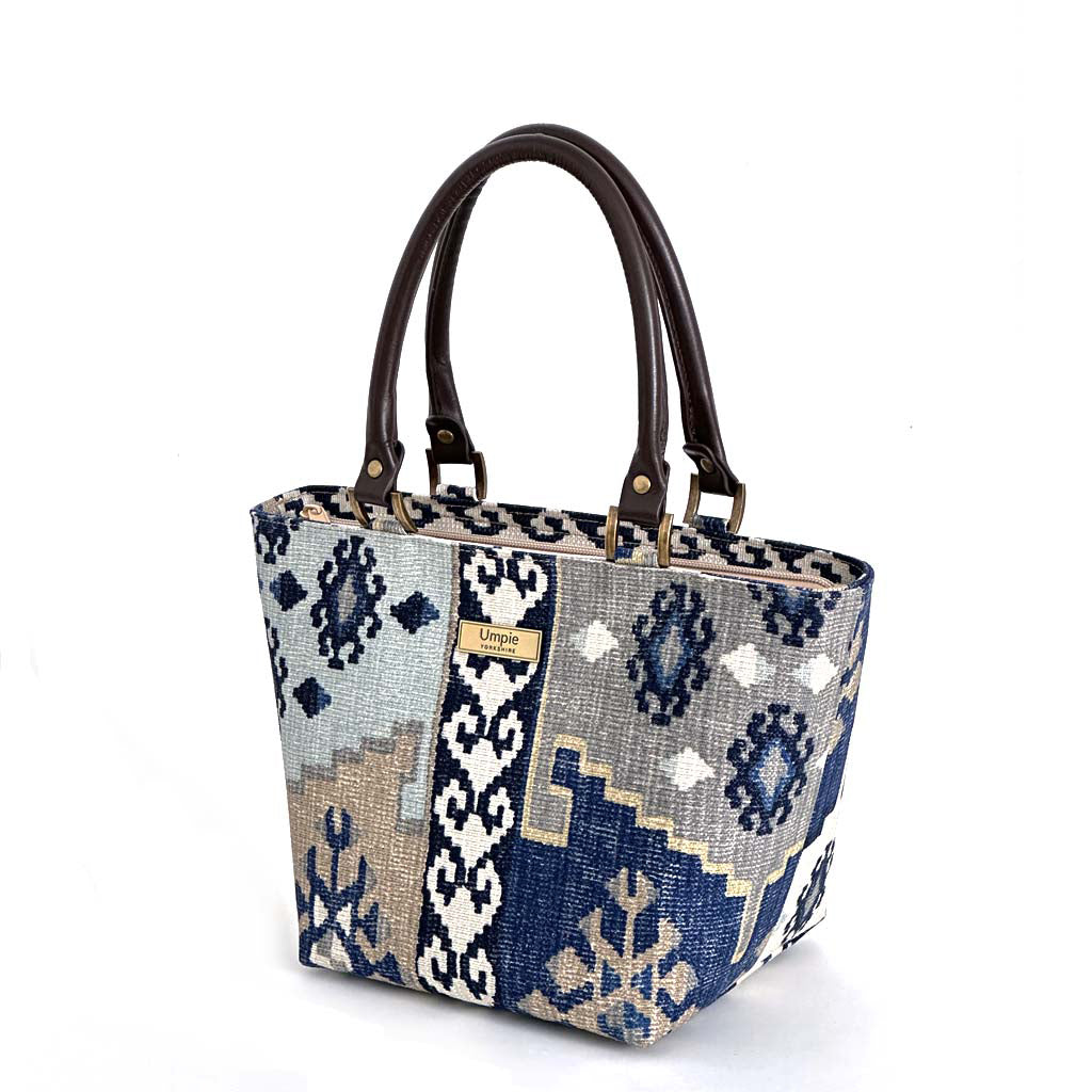 Navy canvas handbag with traditional Kilim geometric pattern in navy, grey, light blue and taupe, brown leather handles, front view by Umpie Handbags