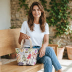 Pink floral linen handbag with beige leather handles, carried by hand against a summer garden backdrop, by Umpie Handbags