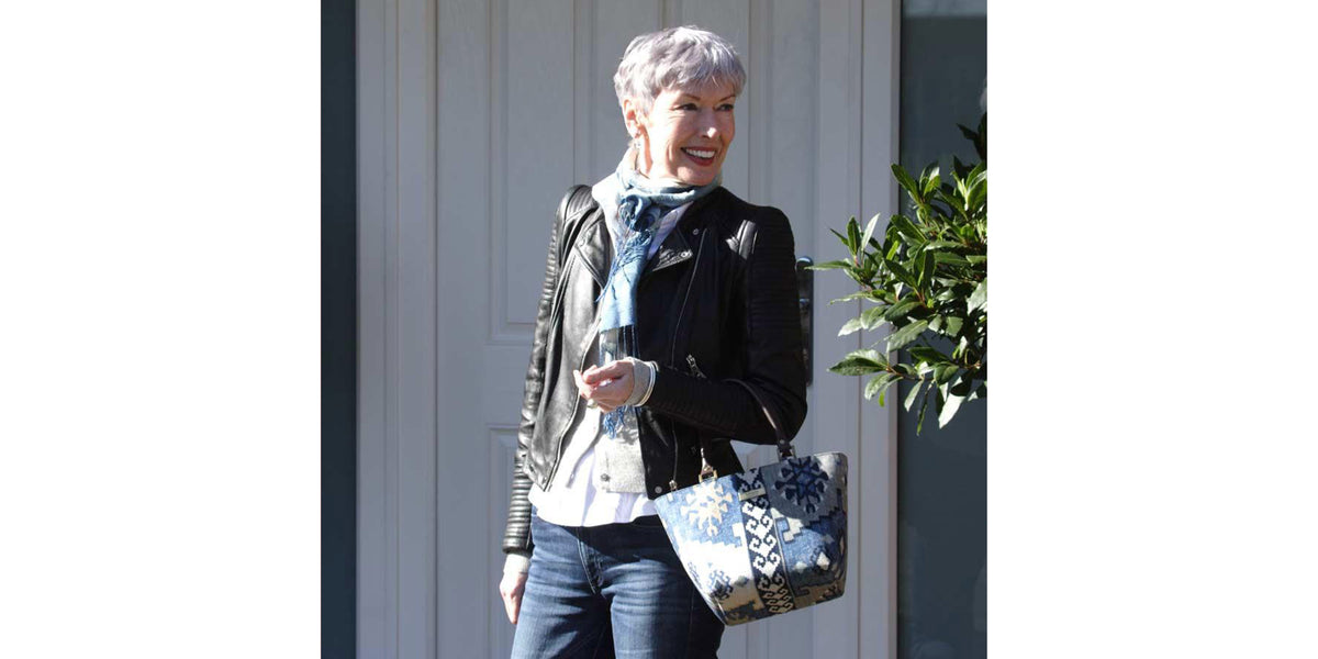 A woman standing in a doorway holding the Navy Kilim Canvas Handbag by Umpie Handbags