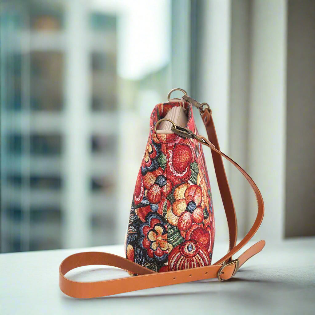 The Red Floral Crossbody Bag with a tan leather strap.