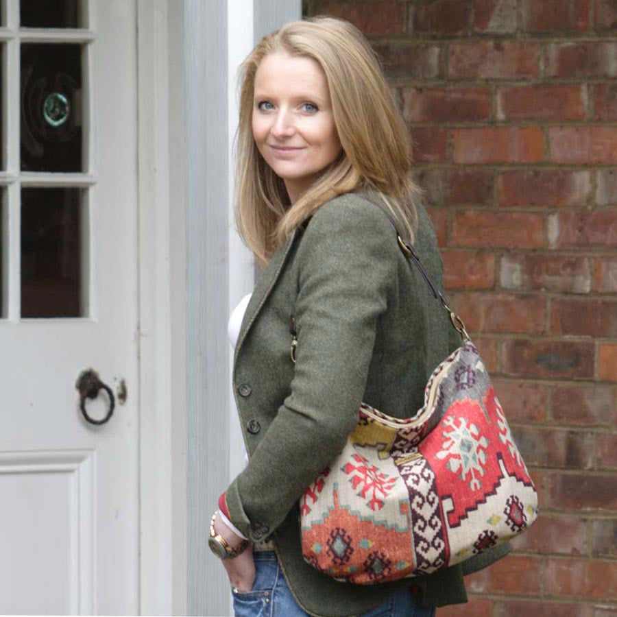 A woman wearing the Red Mix colour, Kilim Design Canvas Hobo Bag With Black Leather Strap by Umpie Handbags