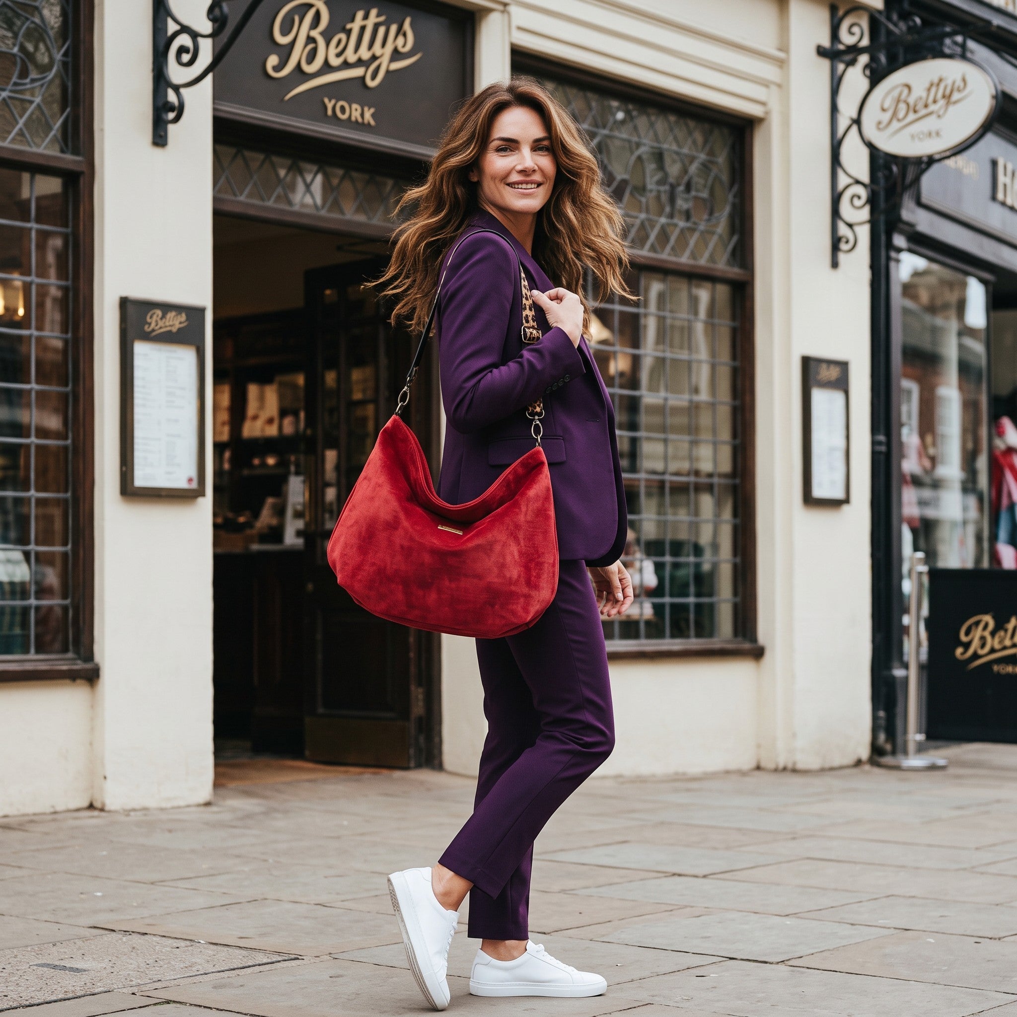 Model wearing the red velvet hobo bag with leopard print leather strap and antique gold hardware, styled with a purple suit — by Umpie Handbags