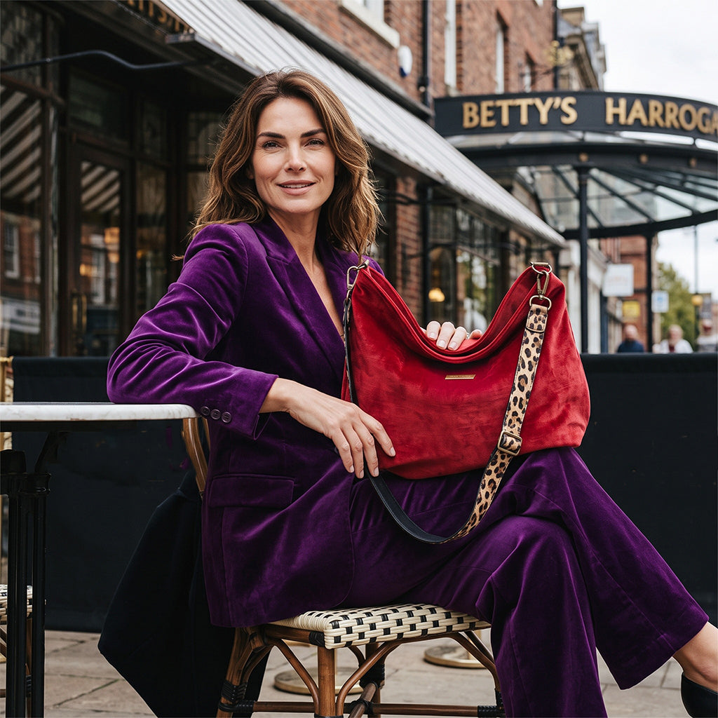 Model wearing the red velvet hobo bag with leopard print leather strap and antique gold hardware, styled with a purple suit — by Umpie Handbags