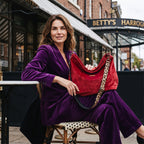 Model wearing the red velvet hobo bag with leopard print leather strap and antique gold hardware, styled with a purple suit — by Umpie Handbags