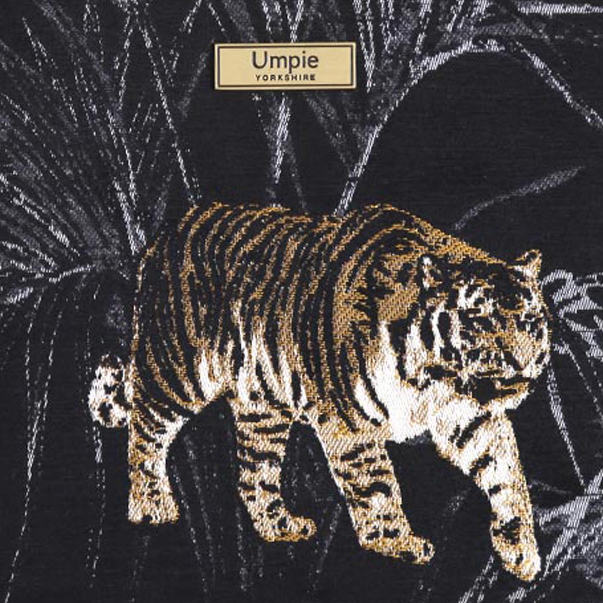 Close-up of vibrant tiger-print tapestry fabric featuring bold gold, black and cream tones with intricate woven texture and artisan craftsmanship by Umpie Handbags