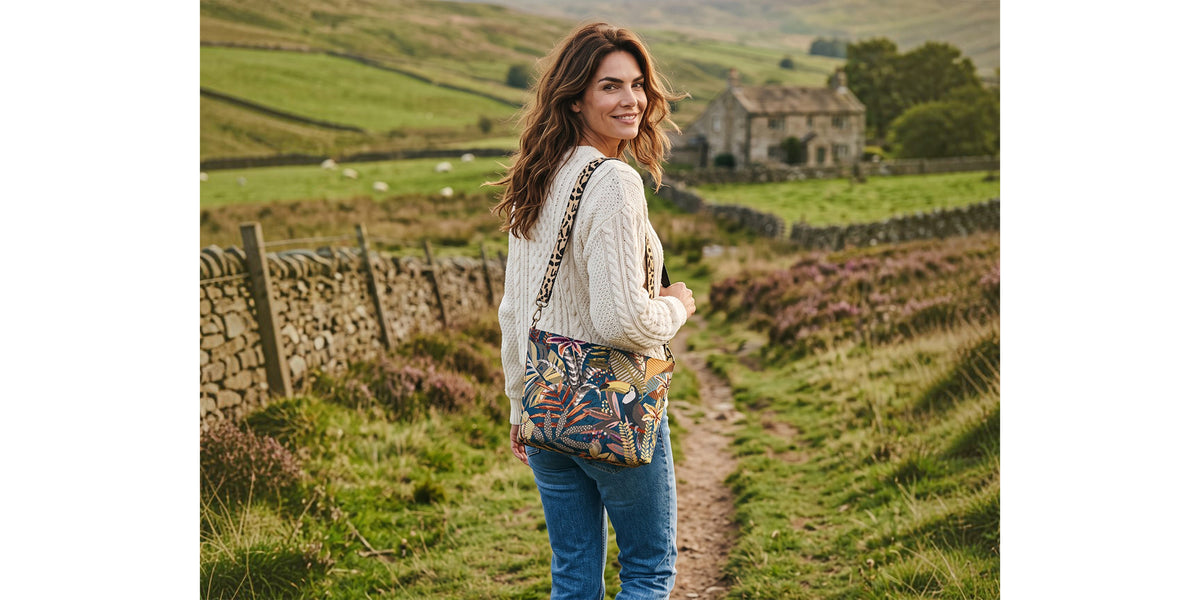 A woman walking down a country lane in the Yorkshire Dales, wearing the Toucan Tapestry Crossbody Bag by Umpie Handbags