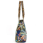 Side profile of Tropical Toucan Shoulder Bag on white background showing generous depth and structured silhouette, tropical tapestry fabric with bold leopard print leather handles, by Umpie Handbags