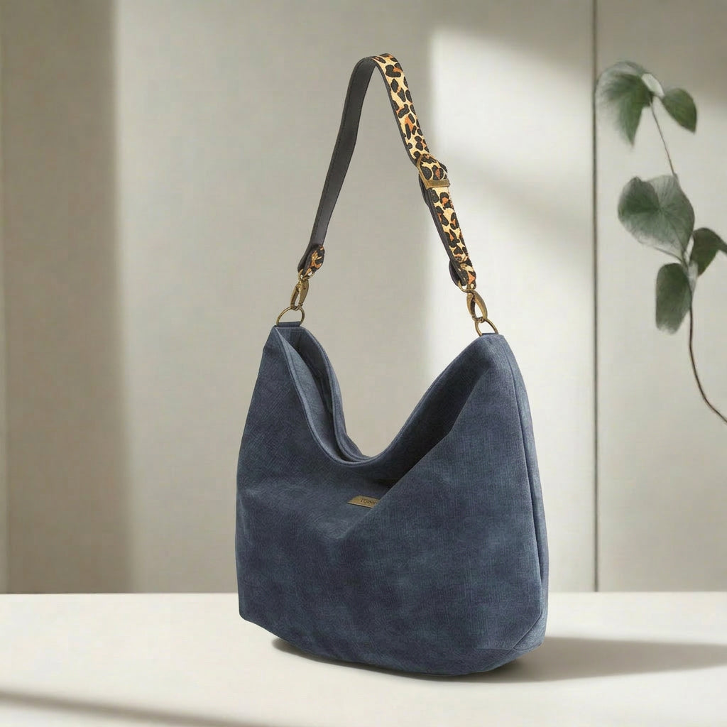 Luxurious blue velvet hobo bag with bold leopard print leather strap, front view showing rich texture and slouchy silhouette by Umpie Handbags