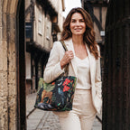 A woman in a cream trouser suit walks through a stone archway in York, carrying the velvet tiger shoulder bag with leopard print strap by Umpie Handbags
