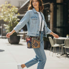 Canvas crossbody bag with vibrant kilim geometric pattern, worn by model in blue denim, adjustable black leather strap, compact silhouette, lifestyle photography by Umpie Handbags
