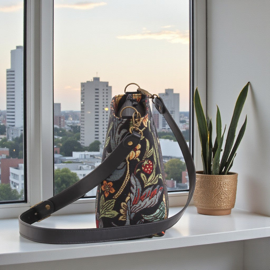 Side profile of William Morris crossbody bag displaying structured silhouette and rich botanical tapestry with black leather accents by Umpie Handbags
