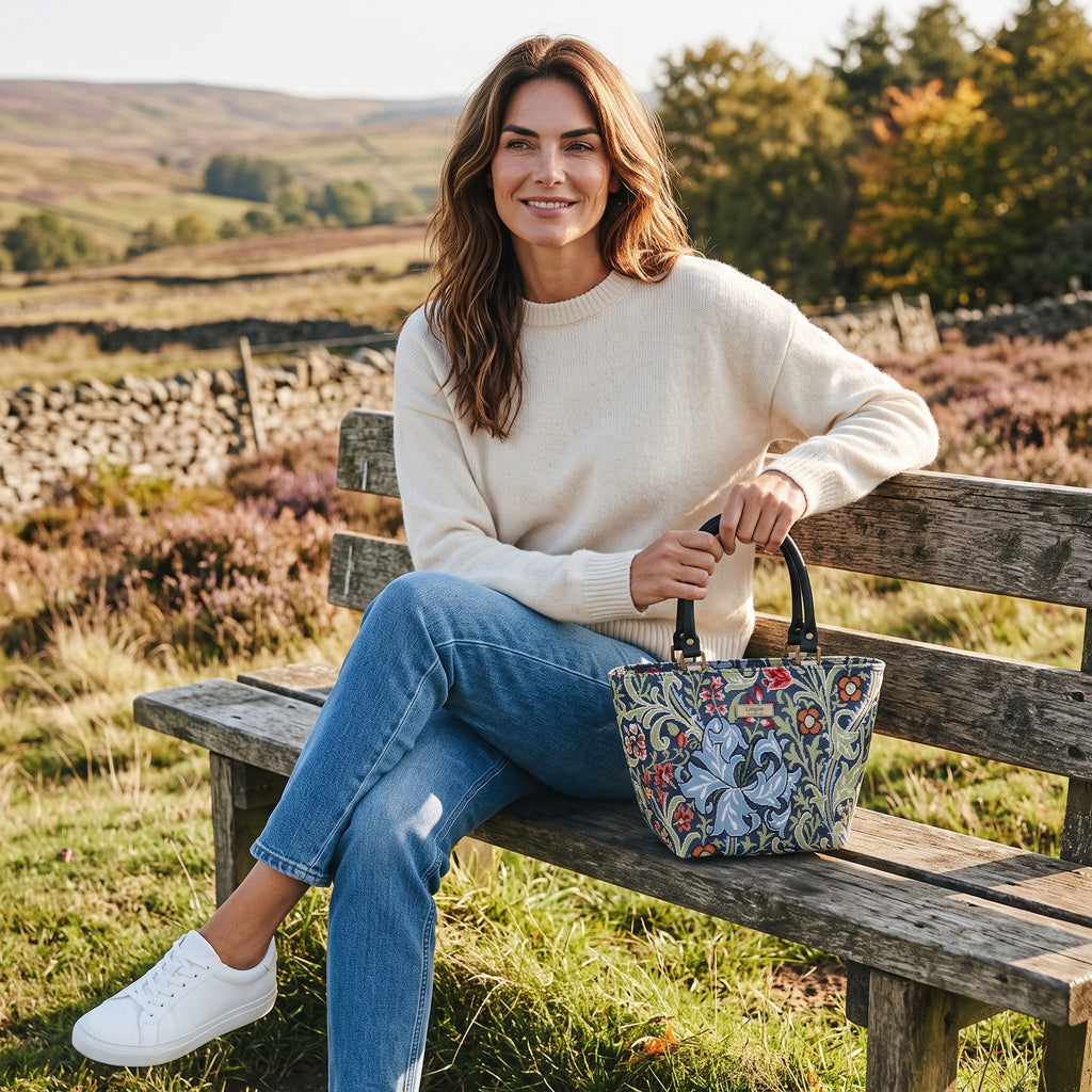 William Morris Handbag held by seated model showing exquisite Golden Lily tapestry design by Umpie Handbags