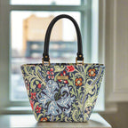 William Morris's floral-patterned handbag with black leather handles, on a surface with a blurred background